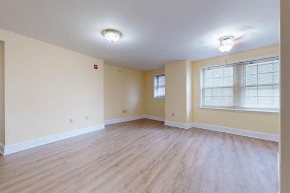 A room with wooden flooring and a window with blinds.