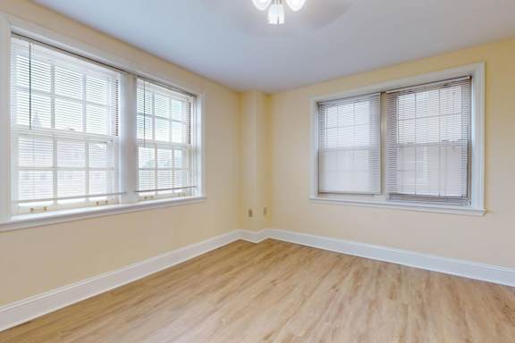 A room with two windows and wooden flooring.