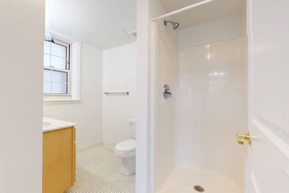 A white bathroom with a toilet, sink, and shower.
