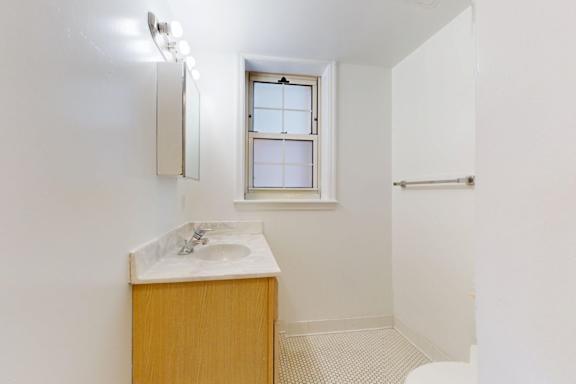 A bathroom with a sink, mirror, and a window.