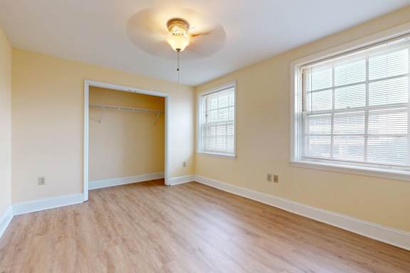 A room with a wooden floor and a window with blinds.