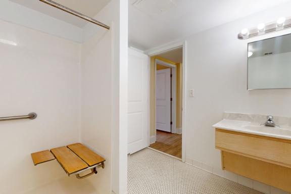 A bathroom with a white sink and a wooden bench.