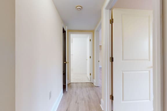 A hallway with white walls and a wooden floor.