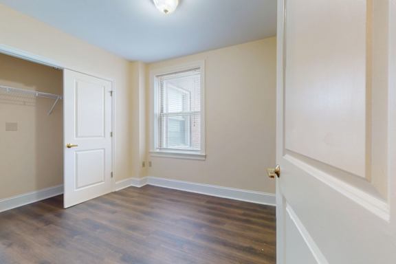 A room with a door, a window, and a wooden floor.