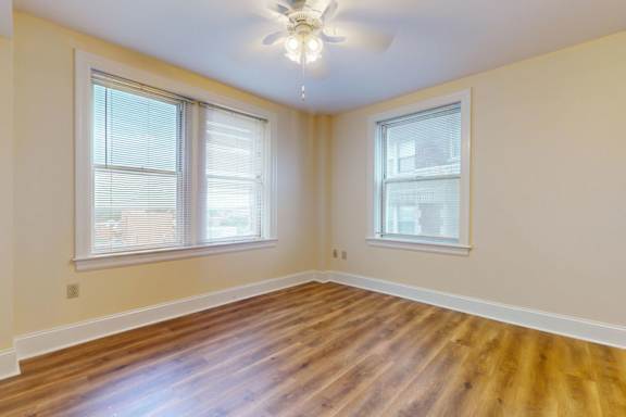 A room with wooden floors and two windows.