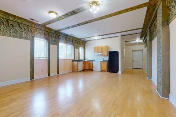 A room with wooden floors and a large window on the left side.