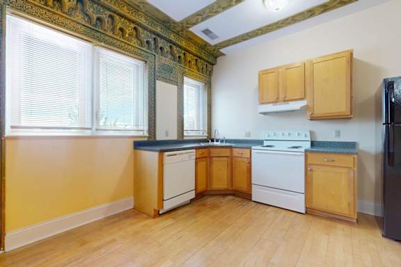 A kitchen with wooden cabinets and a black refrigerator.