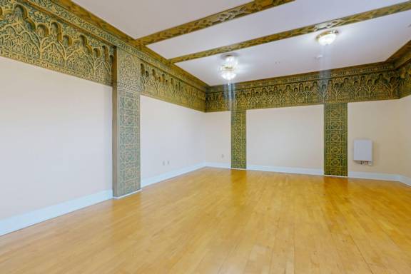 A room with wooden floors and ornate columns.