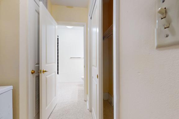 A hallway with a white door and a white wall.