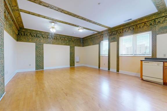 A room with wooden floors and a wall with green and gold decorations.