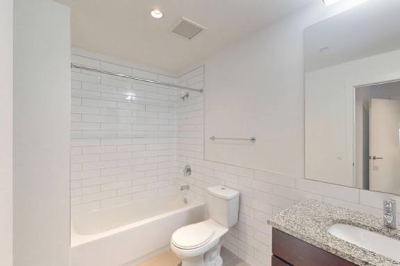 A white toilet sits next to a white bathtub in a bathroom.