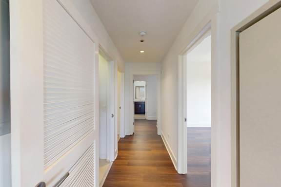 A long hallway with white walls and wooden floors.