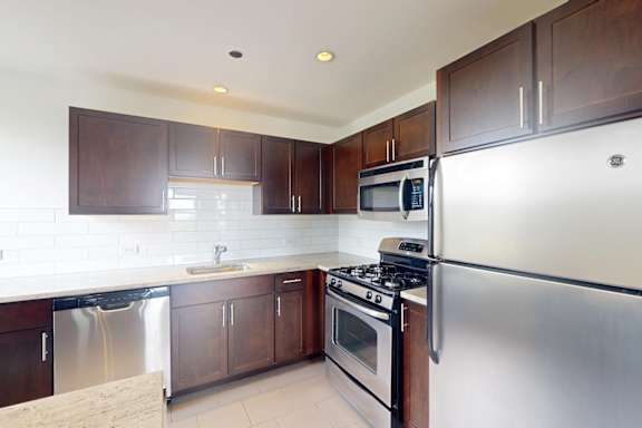 A kitchen with a stove, refrigerator, and microwave.