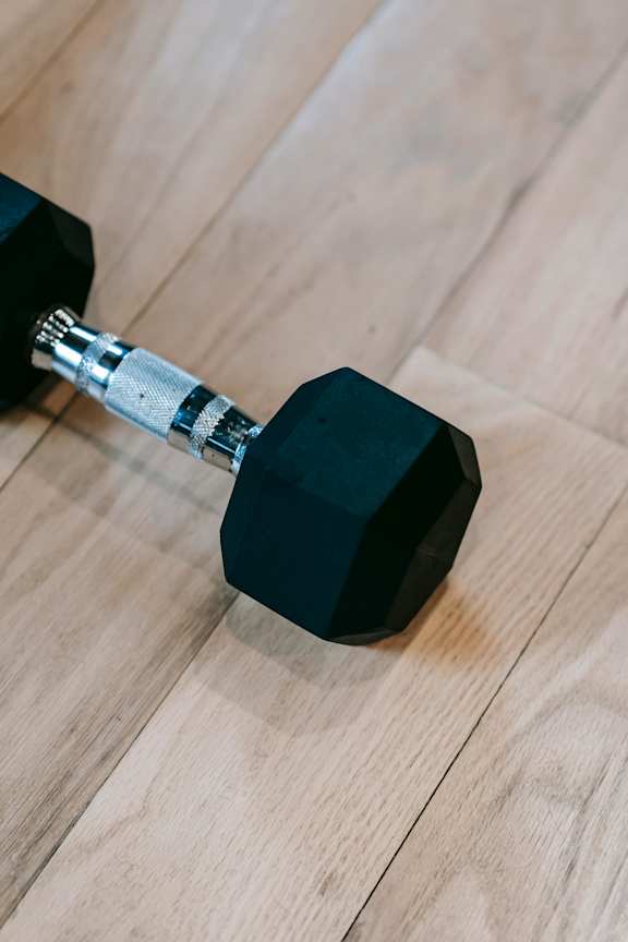 A black dumbbell on a wooden floor.