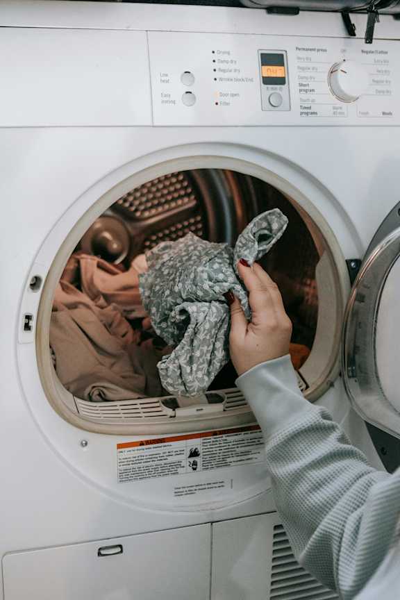 A person is loading a washing machine with dirty laundry.