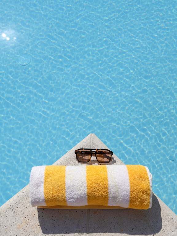 A yellow and white striped towel with sunglasses on top of it.