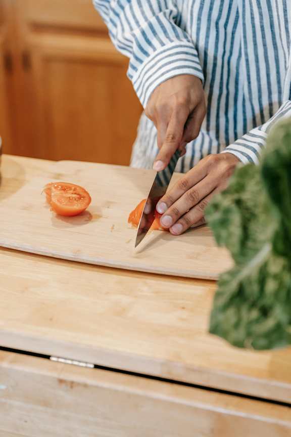 A person cutting a lemon on a wooden cutting board.