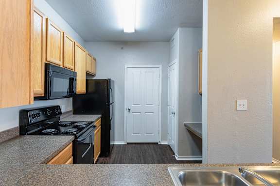 A kitchen with black appliances and wooden cabinets.