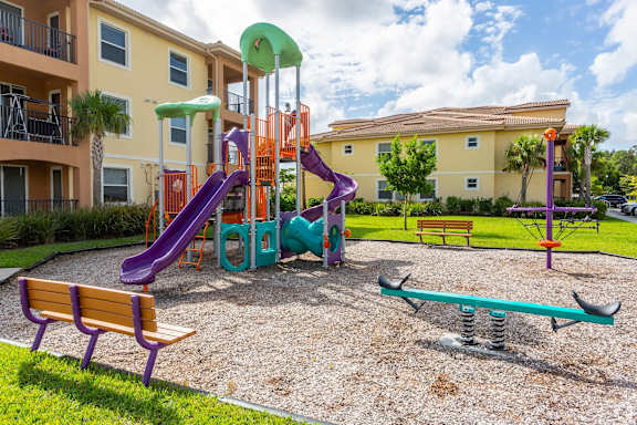 A playground with a purple slide and a wooden bench.