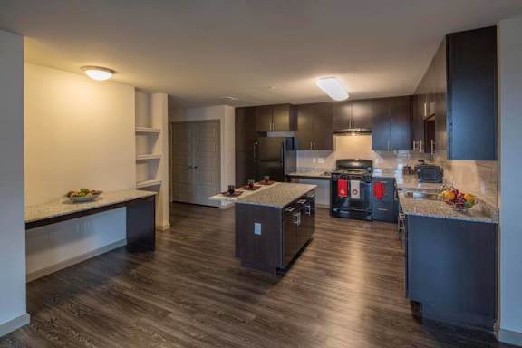 A kitchen with dark wood floors and modern appliances.