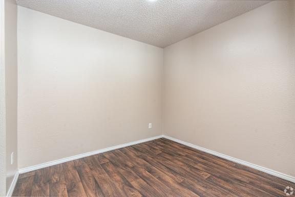 A room with wooden flooring and white walls.