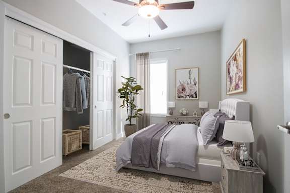 A bedroom with a bed, nightstand, and a ceiling fan.