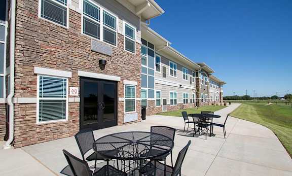 A patio with a table and chairs is in front of a brick building.