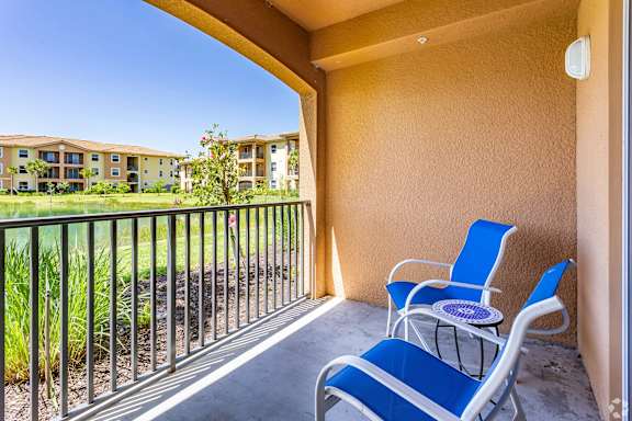 A balcony with blue chairs and a table.
