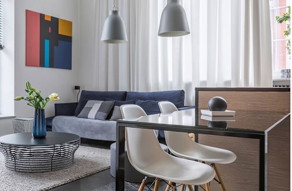 A modern living room with a grey sofa, a coffee table, and a painting on the wall.