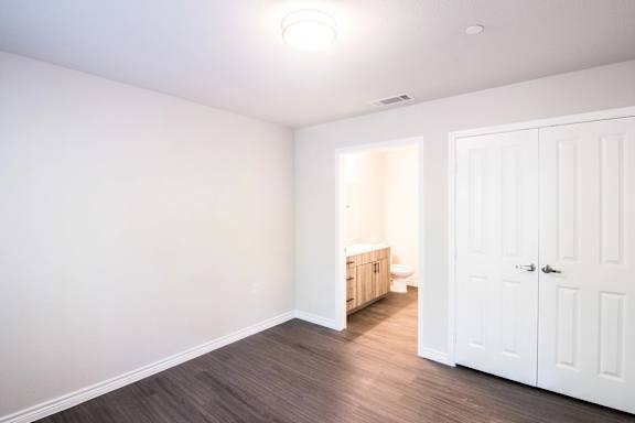 A room with a white door and a toilet visible through the doorway.