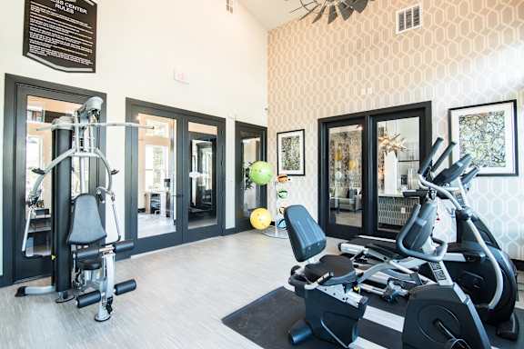 A gym with a variety of equipment including a stationary bike, a leg press machine, and a rowing machine.