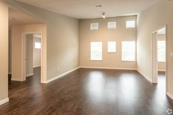 A large empty room with wooden floors and windows.