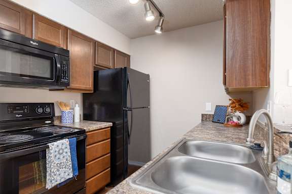 A kitchen with a black refrigerator, black stove, and a black microwave.