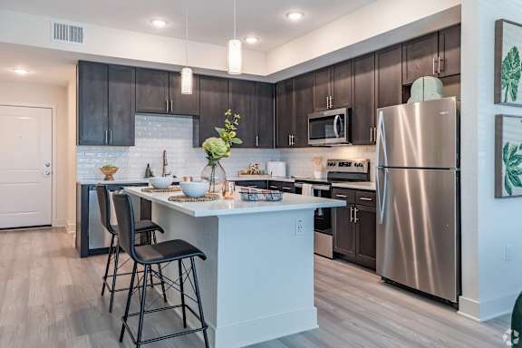 A kitchen with a white island and a stainless steel refrigerator.