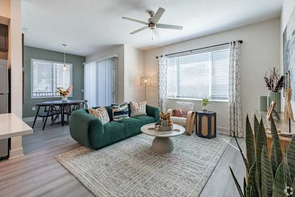 A living room with a green couch, a coffee table, and a ceiling fan.