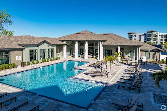 A large swimming pool in front of a building with a sunny day.