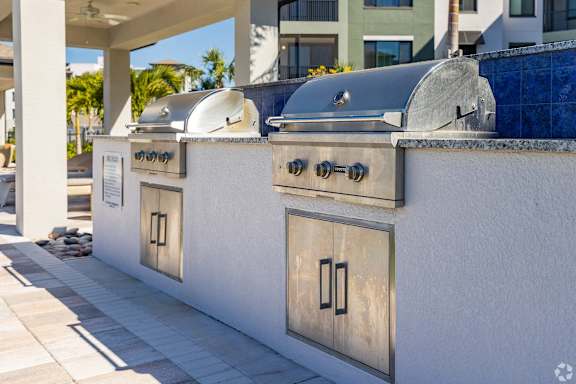 A row of outdoor kitchen grills are lined up on a patio.