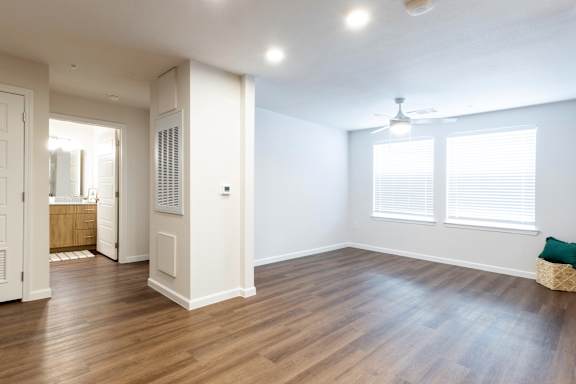 A room with wooden floors and a window with blinds.