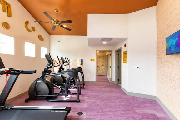A room with exercise equipment and a ceiling fan.