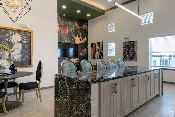 A kitchen with a marble countertop and a dining table with chairs.
