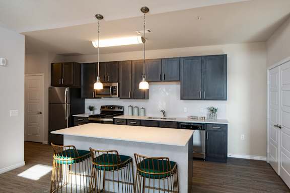 A kitchen with a white island and black cabinets.