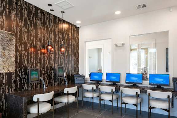 A room with a brown marble wall and a row of computers on desks.