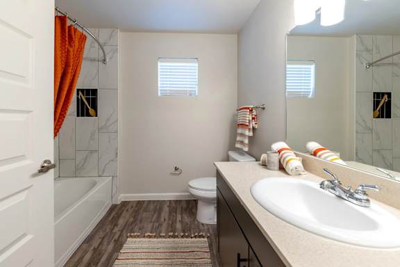 A bathroom with a white sink, toilet, and a shower with a red shower curtain.