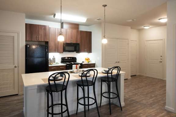 A kitchen with a white island and black bar stools.