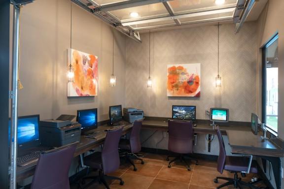A room with a desk and chairs with computers on it.