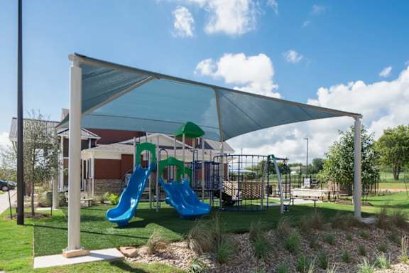 A playground with a blue slide and a green roof.
