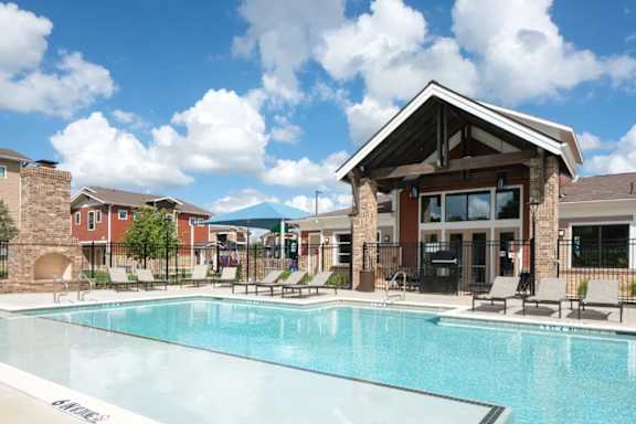 A swimming pool in front of a building with a covered patio area.