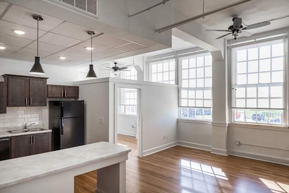 A kitchen with a refrigerator, cabinets, and a marble countertop.