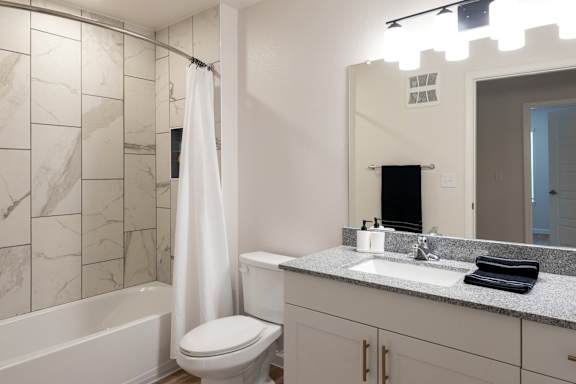 A white bathroom with a marble tile shower.