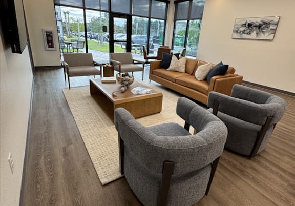 A living room with a grey sofa, two grey armchairs and a wooden coffee table.
